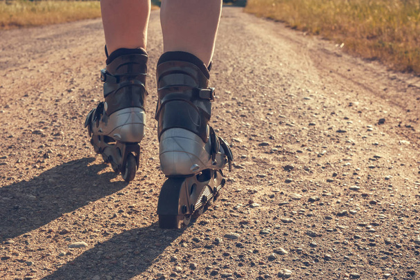 teenage girl rollerblading on the street on the road in the countryside on a summer evening  sunset - Фото, изображение