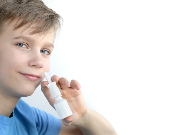 Poika käyttää nenäsumutetta valkoisella pohjalla
 - Valokuva, kuva