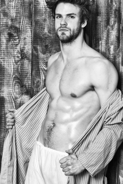Bachelor sexy body chest and belly. Guy shimmering skin undressing bathrobe. Man athlete with fit torso. Sexy attractive macho tousled hair on wooden background. Sportsman show six pack sexy torso - Fotografie, Obrázek
