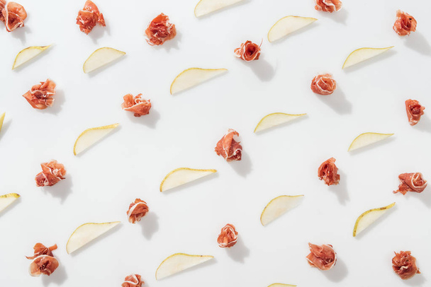 flat lay of prosciutto near sliced juicy pears on white background - 写真・画像