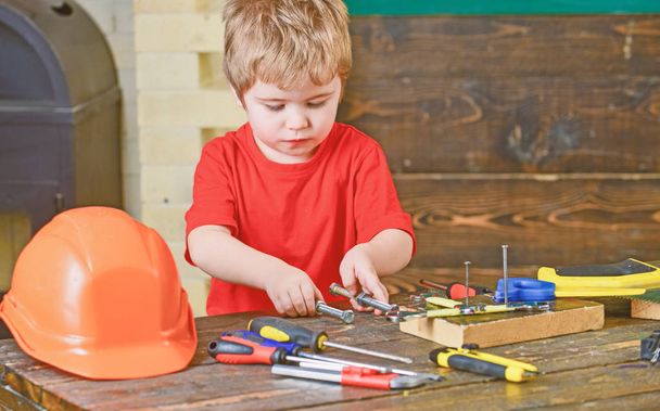 Boy holding two long metal bolts with screw nuts in his hands. Kid playing with tools. Educational game concept - Fotó, kép