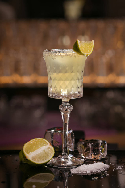 Margarita alcohol cocktail with lime ice. Alcohol cocktail on black background surface. Barmen is making Margarita - Valokuva, kuva