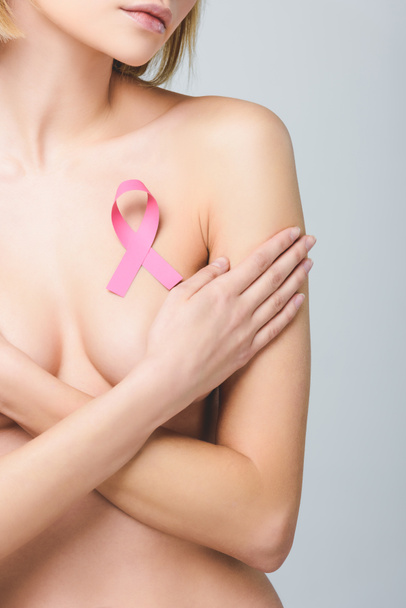 обрезанный вид обнаженной девушки с розовой лентой осведомленности о раке молочной железы, изолированный на серой
 - Фото, изображение