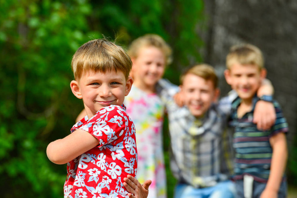 Neljä onnellista ja iloista lasta, poika punaisissa vaatteissa on etualalla, ja hänen ystävänsä ovat takana.
. - Valokuva, kuva