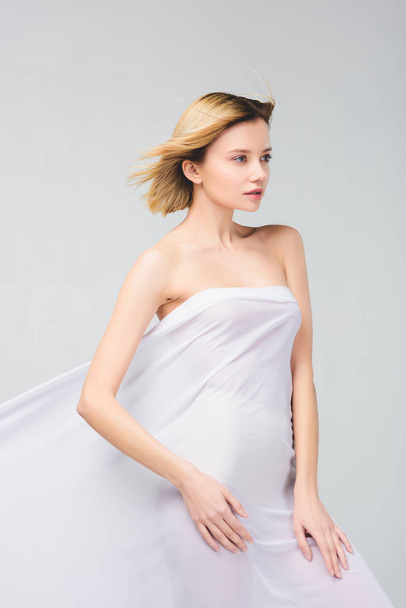 tender naked girl posing in white cloth, isolated on grey - Photo, Image