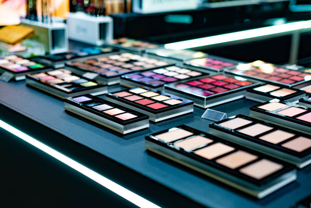 Cosmetics on the shop window with a variety of colors and shades, mascara, powder, paint for beauty and makeup. Consumerism, retail and purchase concept. - Photo, Image