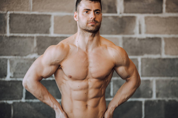 muskulöser Bodybuilder in einem Fitnessstudio, der Bauchmuskeln zeigt. - Bild - Foto, Bild