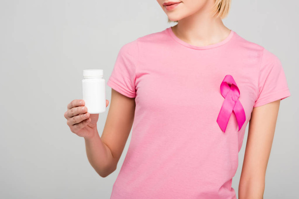 rajattu näkymä tyttö vaaleanpunainen t-paita rintasyöpä tietoisuutta nauha tilalla pullo lääkkeitä, eristetty harmaa
  - Valokuva, kuva