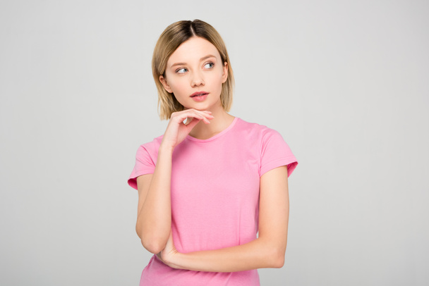 thoughtful blonde woman in pink t-shirt, isolated on grey - Photo, Image