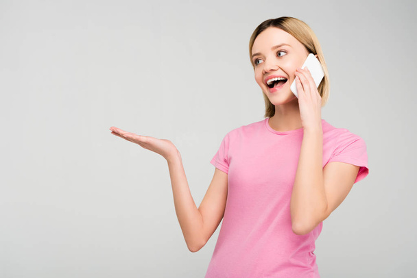 happy attractive girl in pink t-shirt talking on smartphone, isolated on grey - Foto, imagen