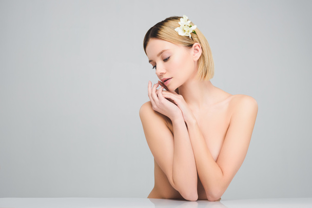 attractive blonde girl posing with freesia flowers in hair, isolated on grey - 写真・画像
