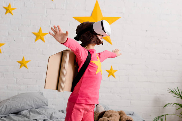 Kid in vr headset and pink clothes waving hands in bedroom - Photo, image