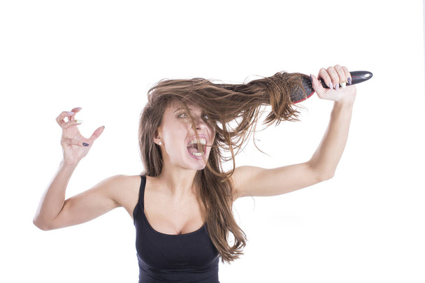 Кричащая злая женщина с расчёской в запутавшихся волосах на белом фоне. Концепция ухода за волосами
 - Фото, изображение