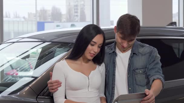 Feliz pareja abrazando, sosteniendo las llaves del coche en el salón de concesionarios
 - Metraje, vídeo