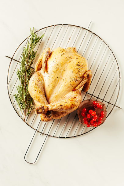 top view of fried chicken, rosemary and berries on metal grille - Photo, image