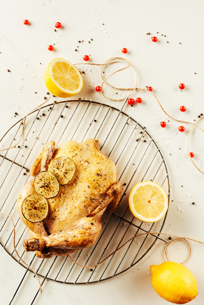 top view of fried chicken and lemons on metal grille with berries and string - Photo, image