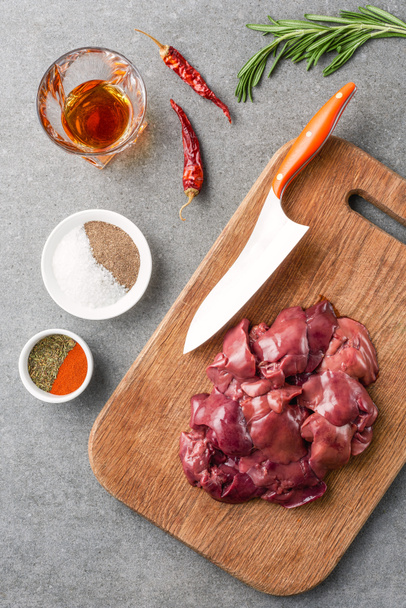 top view of raw meat on cutting board, spices, oil, peppers and rosemary - Photo, Image