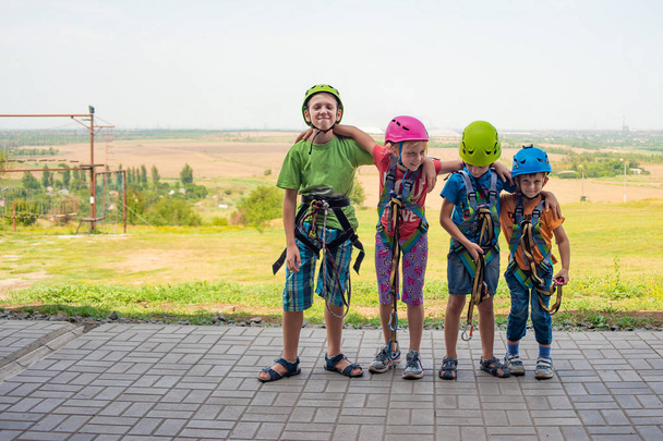 Quatre enfants portent des casques et des vêtements d'escalade et sont prêts à surmonter les obstacles dans un parc extrême
 - Photo, image