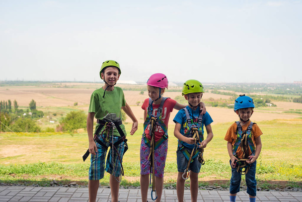 Cuatro niños están usando cascos y ropa de escalada y están listos para superar los obstáculos en un parque extremo
 - Foto, Imagen