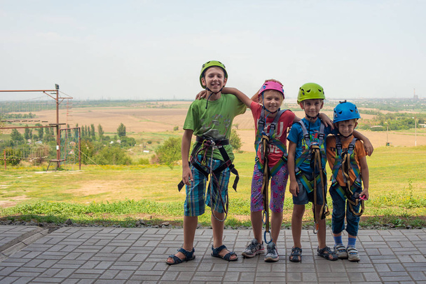 Four children are wearing helmets and climbing clothes and are ready to overcome obstacles in an extreme park - Photo, Image