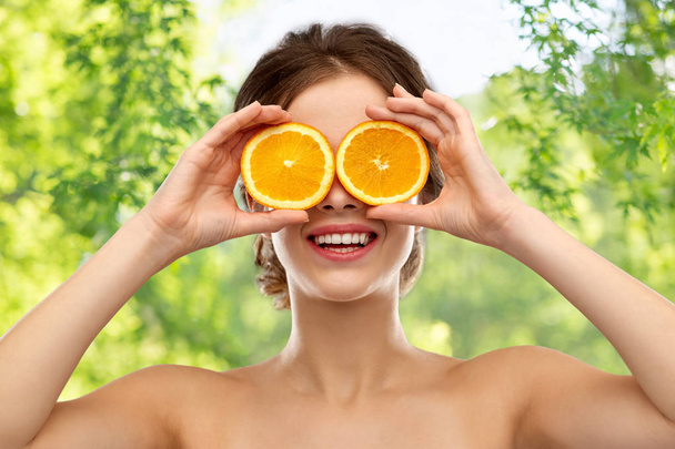 smiling woman with oranges over grey background - Foto, imagen