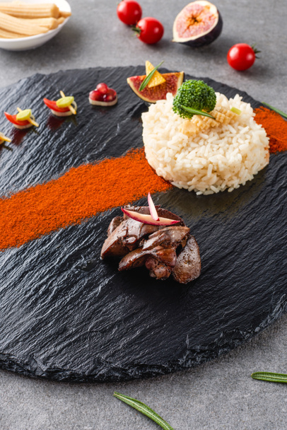 foyer sélectif de riz, brocoli, figue et viande frite sur plaque noire avec des maïs et des tomates cerises
  - Photo, image