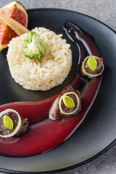 закрытие риса, брокколи, инжира и жареного мяса с соусом на черной тарелке
  - Фото, изображение
