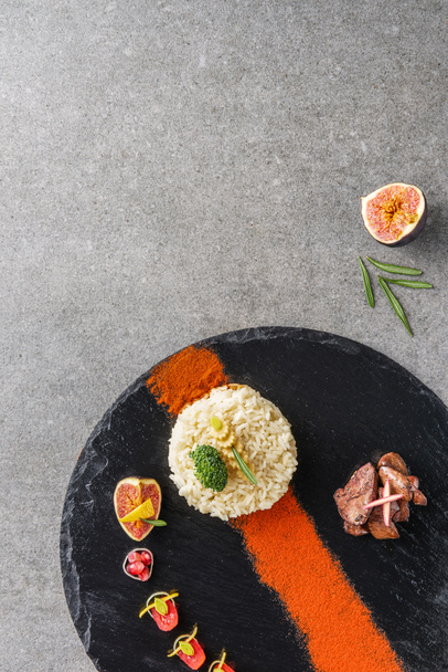 vista dall'alto di riso, broccoli, fichi e carne fritta con salsa su piatto nero
 - Foto, immagini