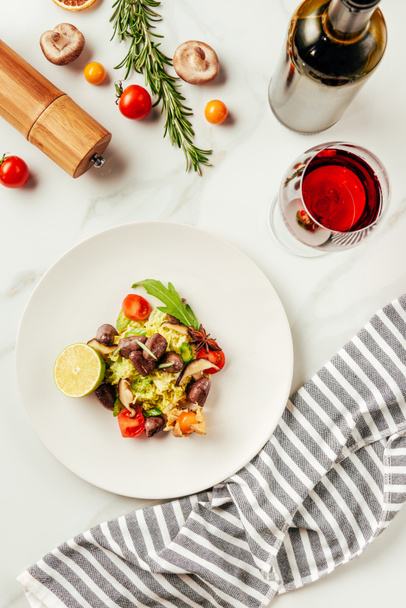 top view of salad on white plate with glass and bottle of wine and cloth - Photo, Image