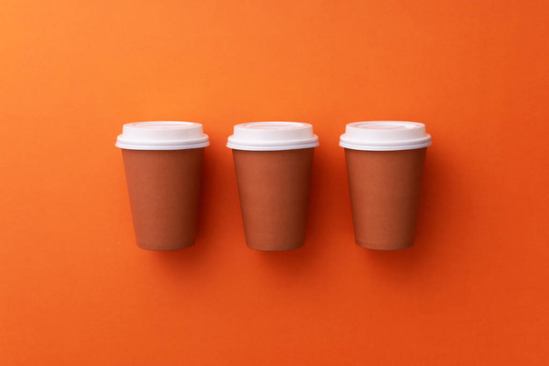 Plusieurs tasses à café jetables organisées sur fond orange
 - Photo, image