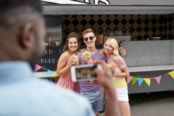 man taking picture of friends eating at food truck - 写真・画像