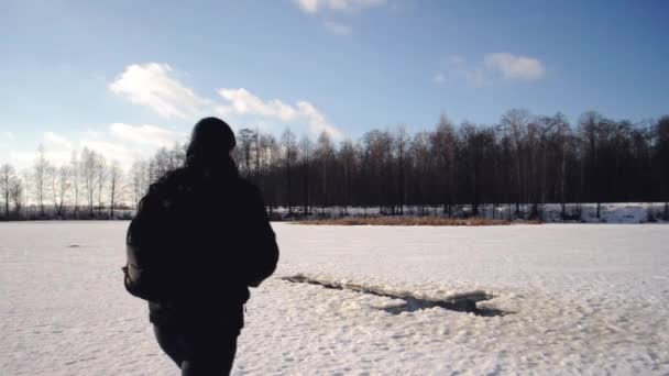 Un homme vêtu d'une veste noire est venu au lac gelé pour nager dans les gelées de l'Épiphanie, tradition russe de nager en hiver
, - Séquence, vidéo