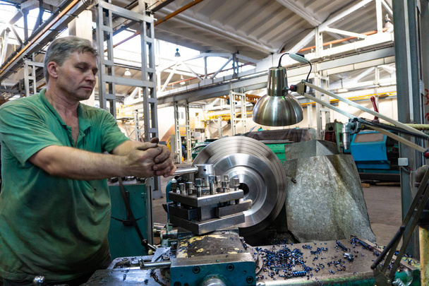 Arbeiter verarbeitet ein Mann Metallprodukte an einer Maschine. Dreharbeiten in der Produktion - Foto, Bild
