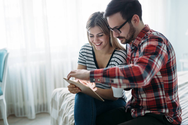 Young happy couple using digital tablet in bedroom - Foto, Bild