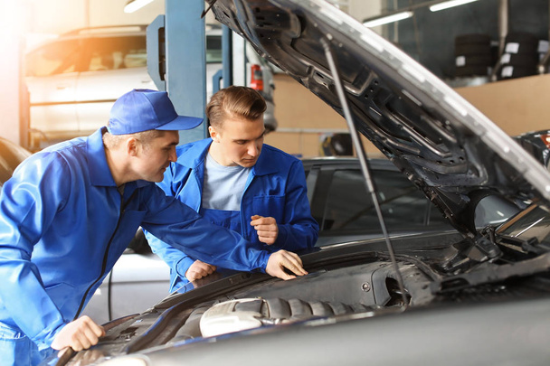 Male mechanics fixing car in service center - Foto, Imagen