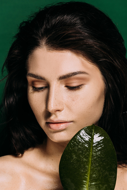 Portrait of beautiful girl with freckles on face posing with leaf isolated on green - Photo, Image