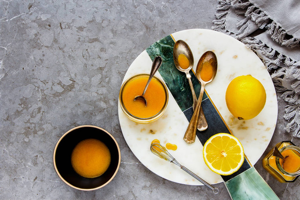 Yummy lemon curd with fresh lemons over grey concrete table background. Top view, flat lay - Image - Photo, Image