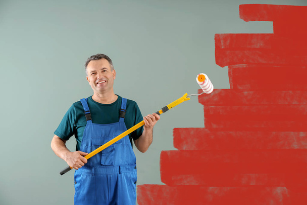 Mannelijke schilder in uniform met rolborstel binnenshuis - Foto, afbeelding