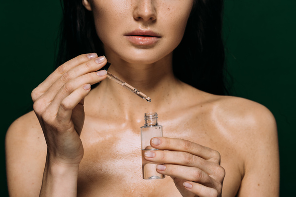 cropped view of naked woman holding bottle with serum isolated on green - Photo, Image