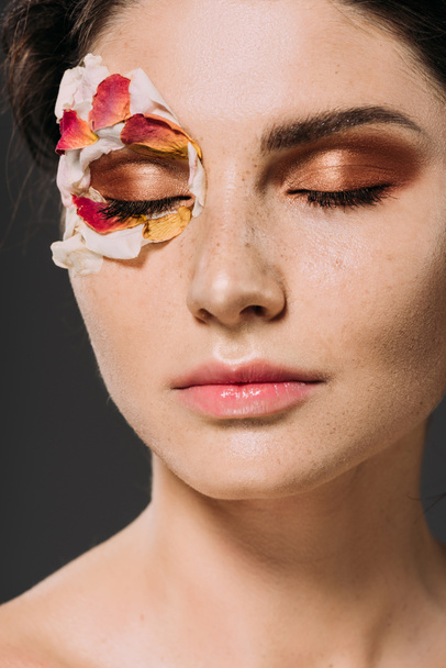 красивая молодая женщина с лепестками и макияжем на закрытых глазах, изолированных на сером
 - Фото, изображение