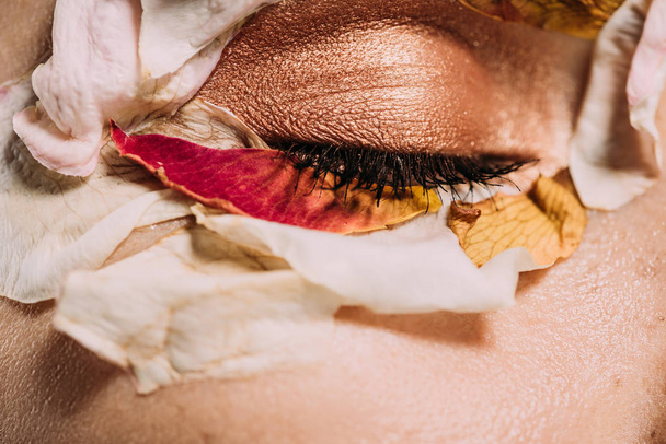 close up of girl with petals and makeup on closed eye  - Fotó, kép