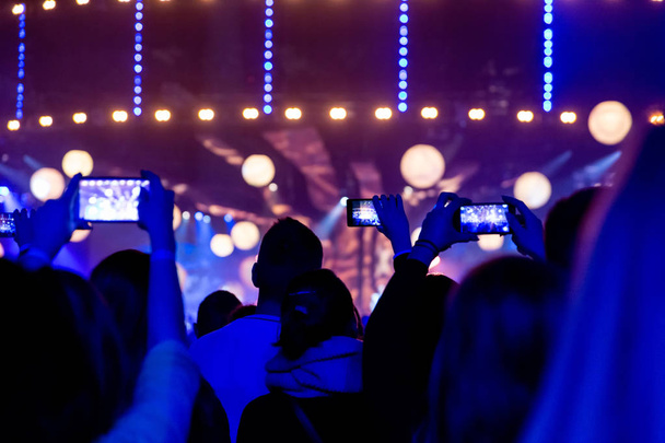 Silhouettes de foules de spectateurs lors d'un concert avec des smartphones dans leurs mains
. - Photo, image