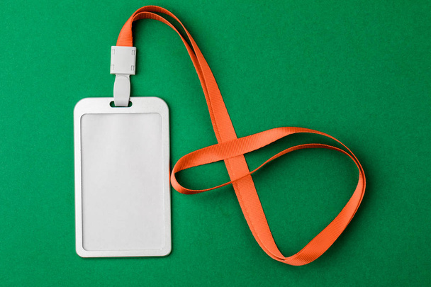 Blank security tag with a red stripe neck on a green background. Place for text, layout. - Photo, Image