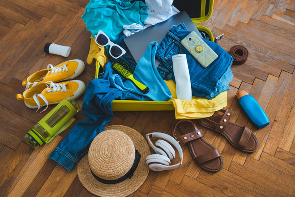 έννοια του ταξιδιού. κίτρινο βαλίτσα με διαφορετικά πράγματα γύρω από αυτό. το top view - Φωτογραφία, εικόνα