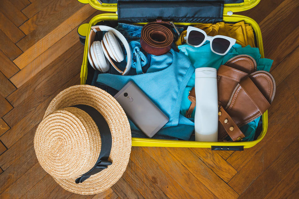 concepto de viaje. maleta amarilla con diferentes cosas a su alrededor. vista superior
 - Foto, imagen