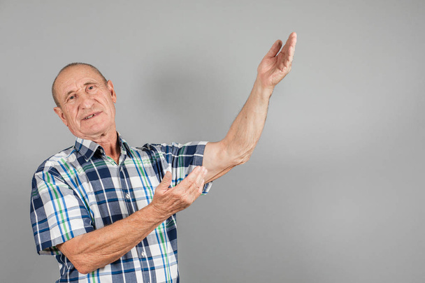 Starší člověk na to jde. Seriózní dospělý muž ukazující prstem na stranu, na šedém pozadí, kopírovat prostor. - Fotografie, Obrázek
