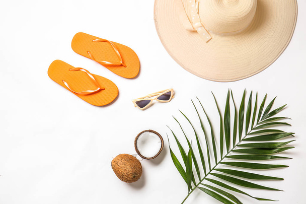 Vrouwelijke strand accessoires met tropische blad en kokos op witte achtergrond - Foto, afbeelding