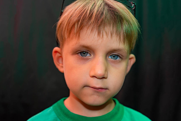 Повсякденний хлопчик в окулярах показує різні обличчя до камери на темному тлі
 - Фото, зображення
