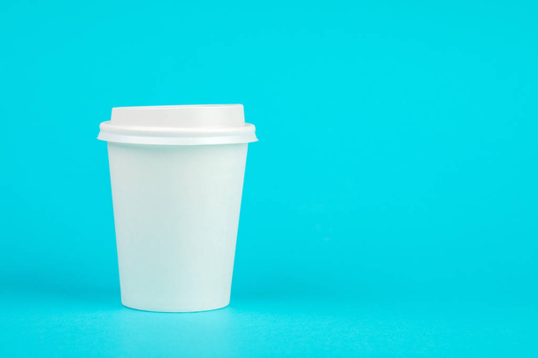 Papier koffie container met witte deksel op blauwe achtergrond. RestaurantgidsTake-away drank container. Drinken van de beker sjabloon voor uw ontwerp. - Foto, afbeelding