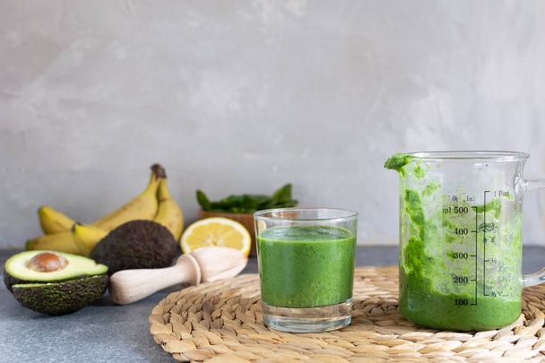 Spring detox, vegetarian breakfast, healthy lifestyle - green superfood spirulina antioxidant smoothie with ingredients, spinach, avocado, lemon, banana, kitchen table, copy space - Foto, immagini
